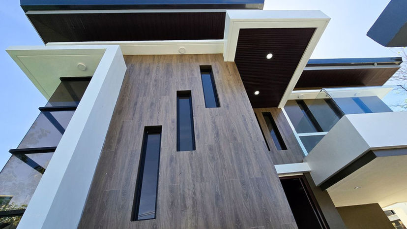 Discover a modern two-story residence in Paranaque, featuring 4 spacious bedrooms, 6 bathrooms, and additional rooms for maid and driver. This home includes an inviting family area, a roomy kitchen with a cozy nook, and a 3-car garage. Enhanced privacy with a remote control gate and beautifully landscaped outdoor spaces perfect for gatherings. The contemporary design showcases sleek lines, a neutral color palette, and large windows for natural light. Ideal for families, this home promotes social interaction and luxury living.