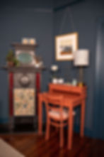 Colour-drenched space featuring midnight blue walls, skirting boards, and door with a terracotta desk and matching chair. The room includes a vintage-style fireplace, a framed artwork, and decorative plants, creating a bold yet cohesive atmosphere.