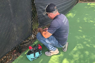 Maintenance Boy technician repairing a tennis court windscreen for an HOA in Naples, FL
