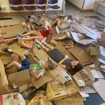 A group of youth in a pile of destroyed cardboard buildings
