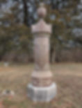 Stone pillar with "TWIST" text and urn on top in a rural setting, surrounded by bare trees and grass. The mood is serene and historic.
