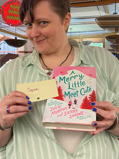 Christin - Circulation Clerk - Standing at the circulation desk holding a book
