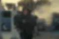 A person in a hoodie runs from a smoking car accident on a city street, with an intense expression. Background includes damaged vehicles.
