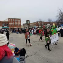 Library Staff Walking in the Christmas Parade holding the Vespasian Warner Library banner