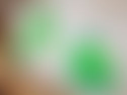A white bulletin board with three pine trees in two toned green construction paper with hand colored ornaments
