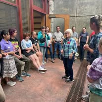 A master gardener standing in the library's sunken gardens talking to a group of teens about planting for pollinators