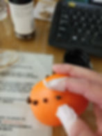Photo of an orange pomander with cloves in the background
