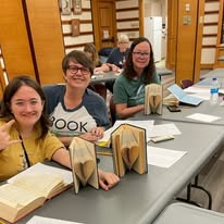 Three ladies with their books with pages folded to look like a heart