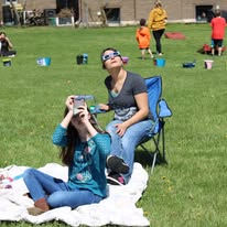 Several people watching the solar eclipse on the library lawn