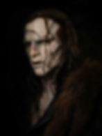 Creepy figure with pale, cracked skin and long hair, wearing fur in a dark setting. The mood is eerie and intense.