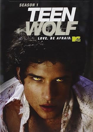 Young man with glowing eyes in a torn shirt under "Teen Wolf" text. Dark background, intense mood. "Love. Be Afraid." Season 1. MTV logo.