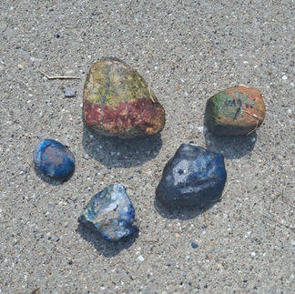 5 colorful pet rocks on a sidewalk