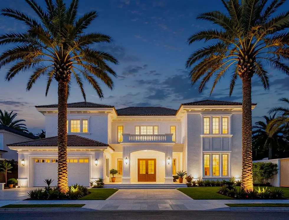 Estate home at night with landscape lighting and large palms
