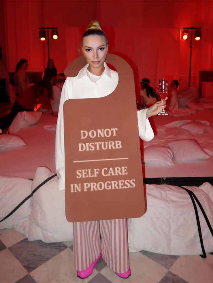 Nikki Trubetskaya on stage holding a sign in a theatrical comedy performance.