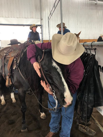 Person in a cowboy hat hugging a saddled horse.