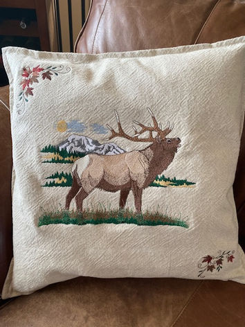 Embroidered pillow with elk in mountain landscape