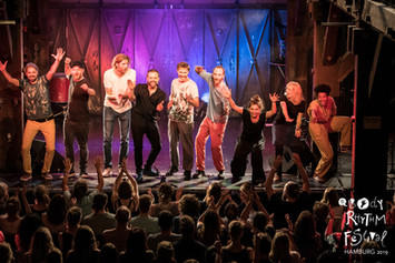 Gruppe von Leuten auf der Bühne, text: Body Rhythm Festival Hamburg 2019.