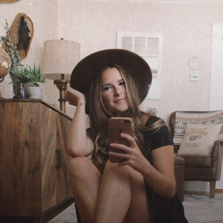 Michaela Hession of Michaela Hession Photography taking a selfie in a mirror in a black dress and black hat