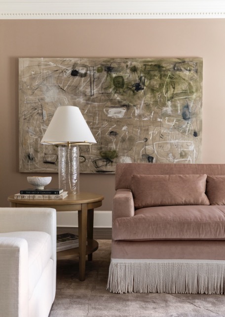 Velvet sofa with bullion fringe, abstract artwork, and layered living room styling details