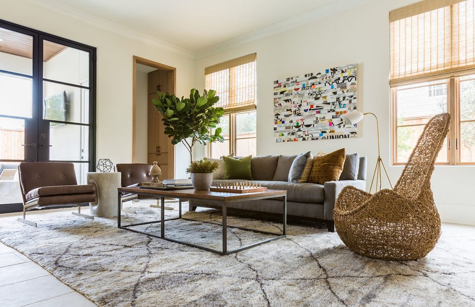 Modern living room with a gray sofa, brown chairs, and a woven chair. A vibrant abstract painting adorns the wall, creating a cozy feel.