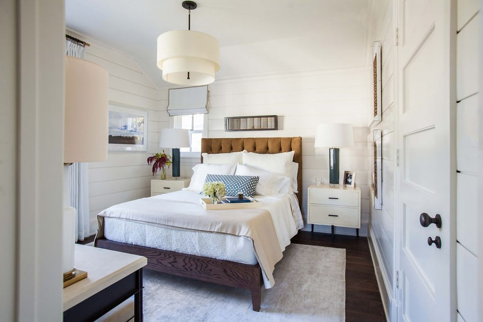 Cozy bedroom with a plush bed, white bedding, and patterned pillows. Soft lighting from lamps, neutral tones, and contemporary decor.