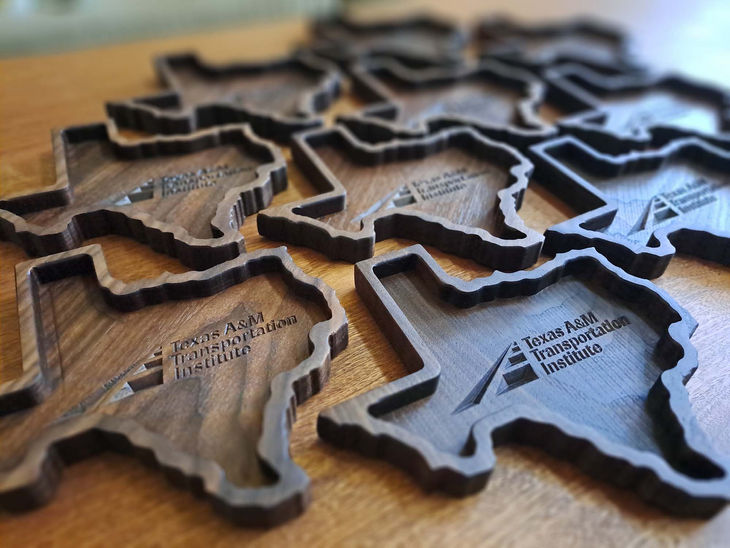 Walnut catchall trays with Texas A & M Transportation Institute engraved in the middle.