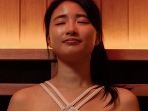 Woman seated comfortably inside an infrared sauna, enjoying a moment of calm and relaxation.