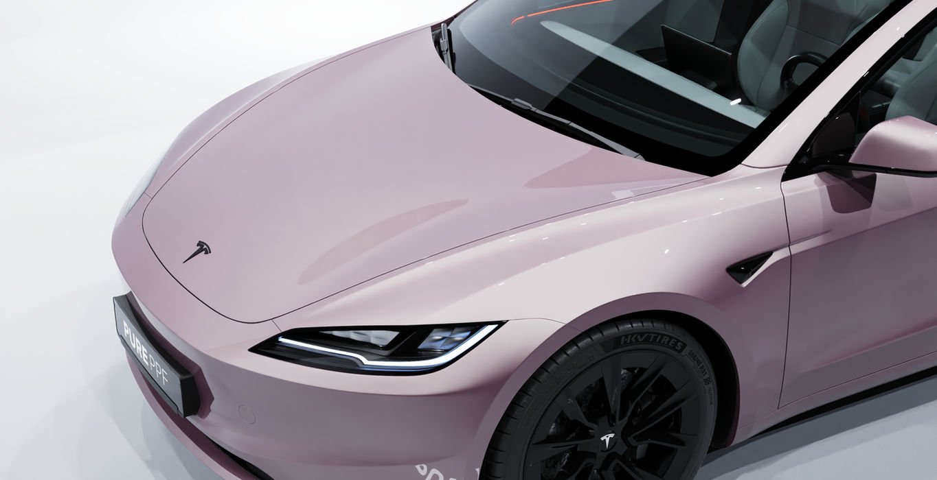 Close-up of a Tesla Model 3's front, wrapped in PurePPF Metallic Rose, highlighting the detailed vibrant light pink rose finish with a glossy and gold metallic appearance, adding a striking and contemporary look.