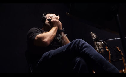 Moody photo of Kent Parker playing harmonica in his New Harmony, IN studio