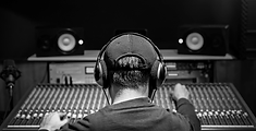 A music producer sitting at a mixing desk