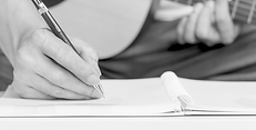 A man writing music while holding a guitar