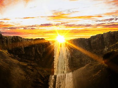 A sun setting behind a waterfall