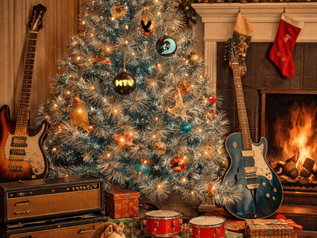 A vintage Christmas tree with blue tinsel, musical instruments, ornaments, a fireplace, and classic holiday decorations in a cozy living room