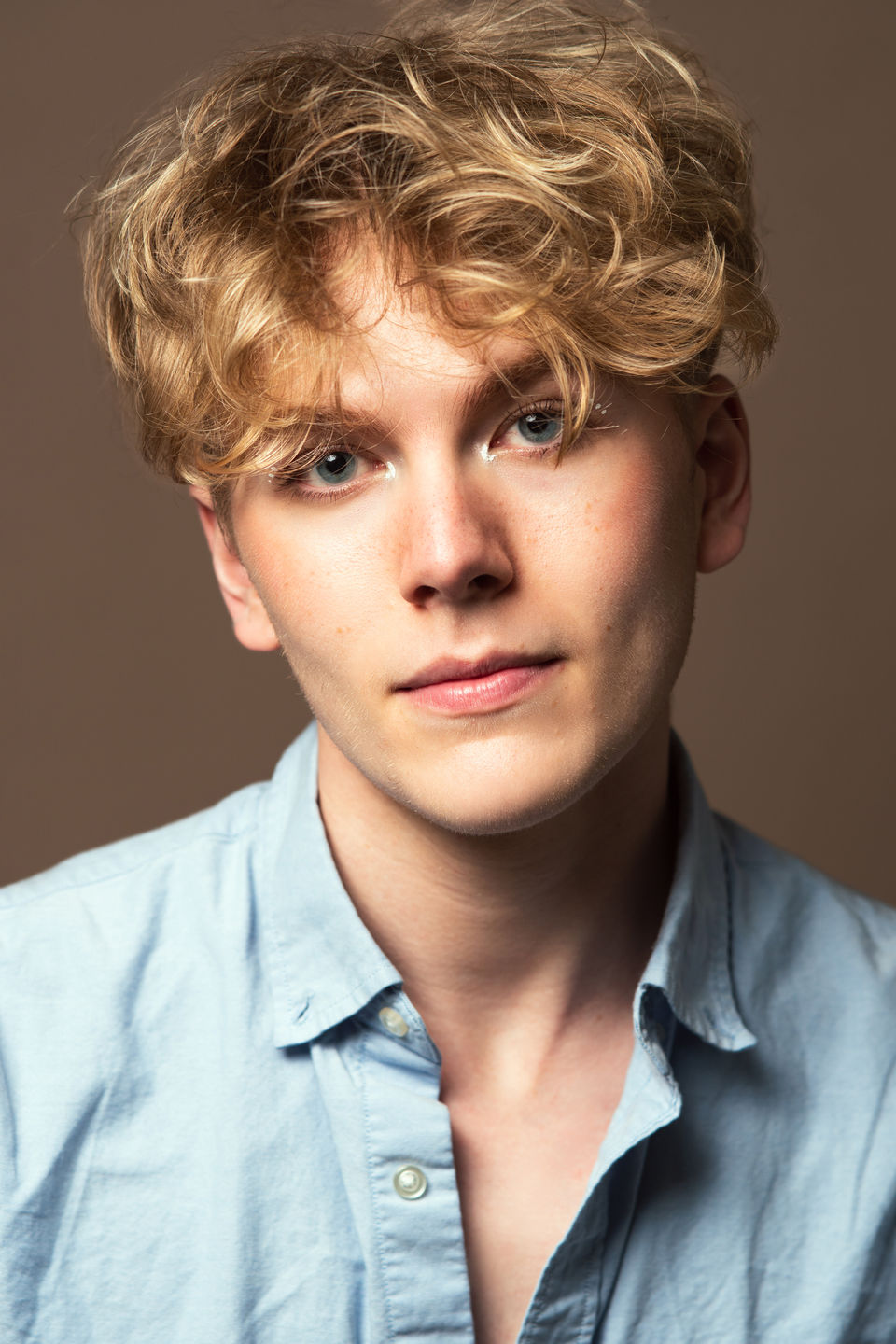 Headshot of young man with blonde hair looking intently at the camera.