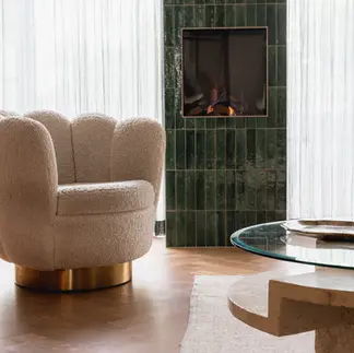 Interieurfoto van houten tafel met glazenblad met op de achtergrond een crème kleurige stoel en een haard van groene tegels