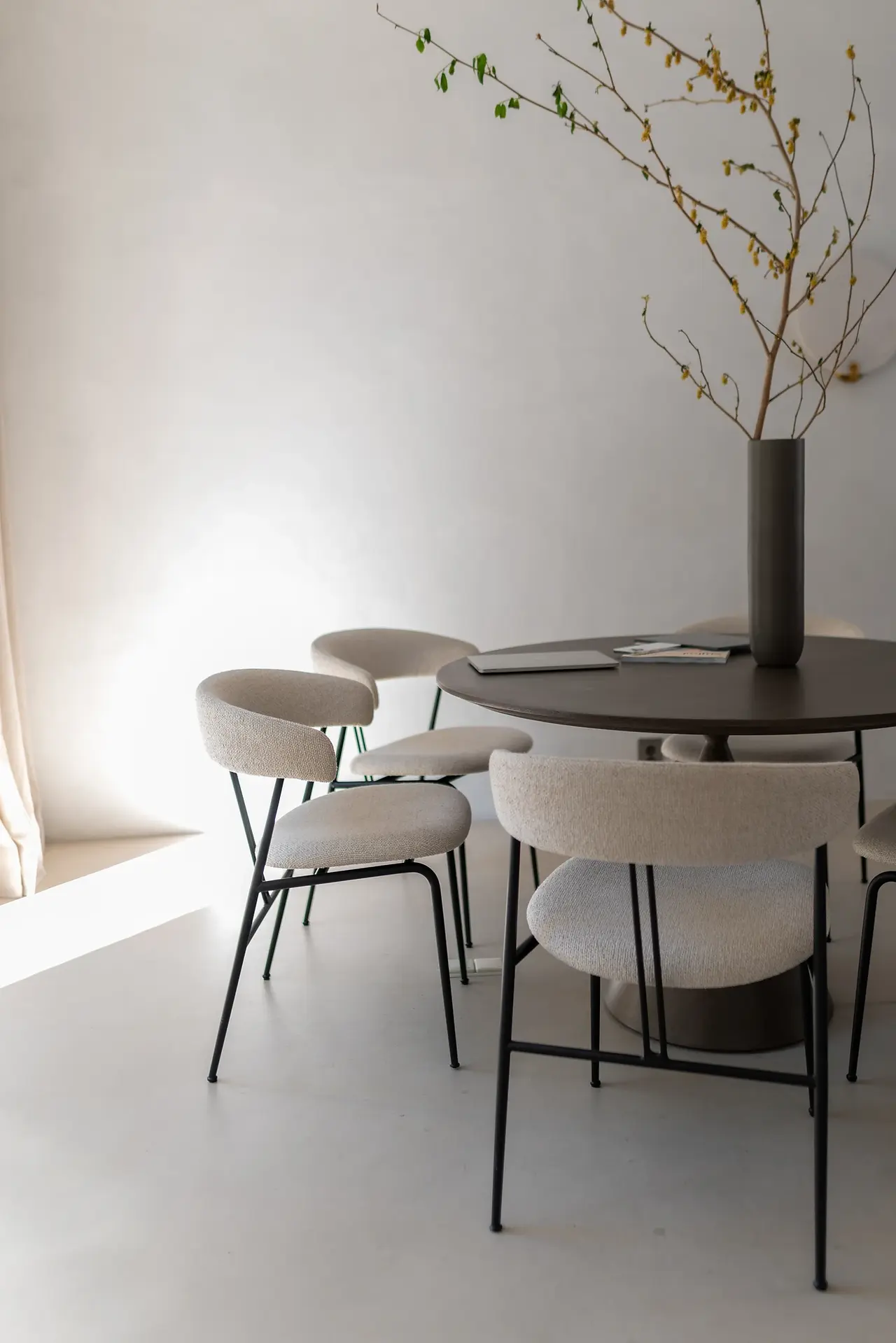 Interieurfoto van een zwarte ronde eettafel met daaromheen 4 crèmekleurige stoelen