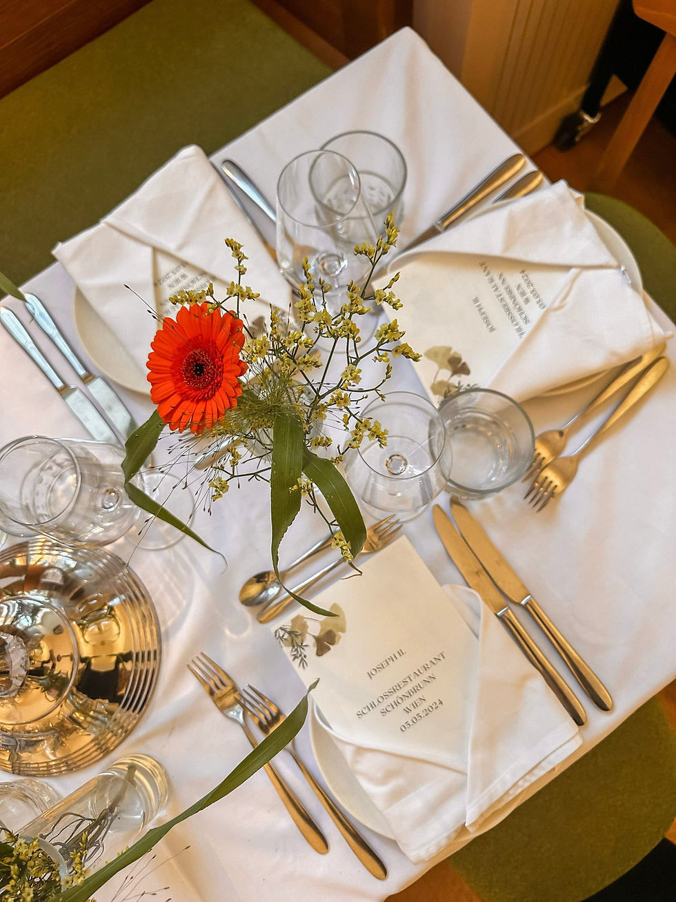 Gedeckter Platz im Joseph II. mit goldenem Besteck und Gerbera