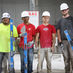 Four bricklayer training participants holding tools at their training site