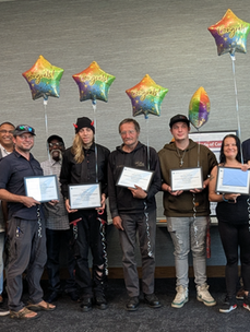 A group of students showing training certificates with balloons behind them.