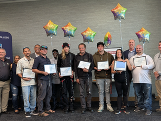 A group of students showing training certificates with balloons behind them.