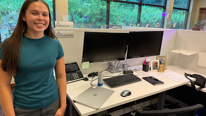Student standing next to desk with multiple computer monitors