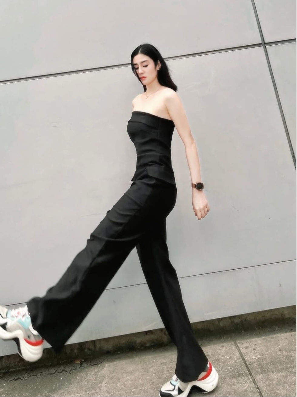 Woman in black strapless top, wide pants, and sneakers
