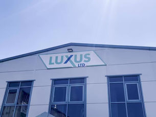 Front view of a Luxus Ltd building with the company logo displayed on the upper facade, set against a clear blue sky.