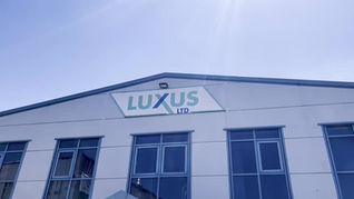 Front view of a Luxus Ltd building with the company logo displayed on the upper facade, set against a clear blue sky.
