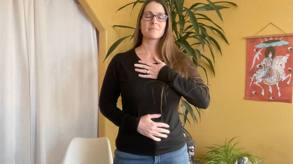 A woman practices a grounding exercise, calmly placing her hands on her chest and stomach to reconnect with herself in a peaceful setting.
