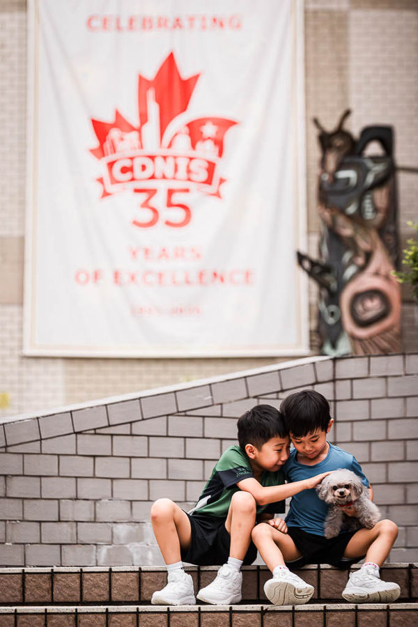 There’s something deeply nostalgic about school uniforms. They represent a chapter of pure joy, daily laughters, and friendships that shape who they are. 🌿
Looking at these beautiful moments captured right outside CDNIS 🇨🇦. The iconic red roof, the running steps, and those genuine, candid smiles in their favourite school tees. Every corner holds a piece of their childhood milestone.