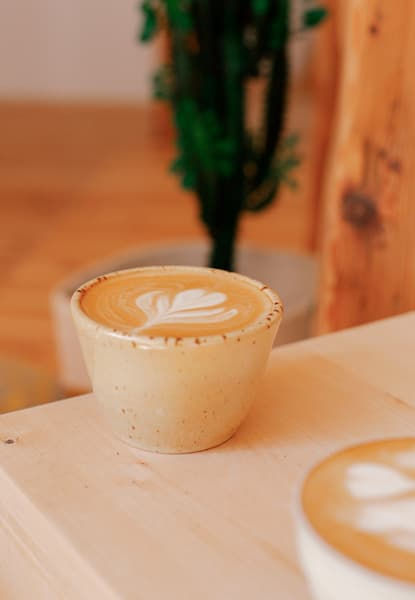 Café de especialidad Café Kilapura servido en taza sobre una mesa de madera.