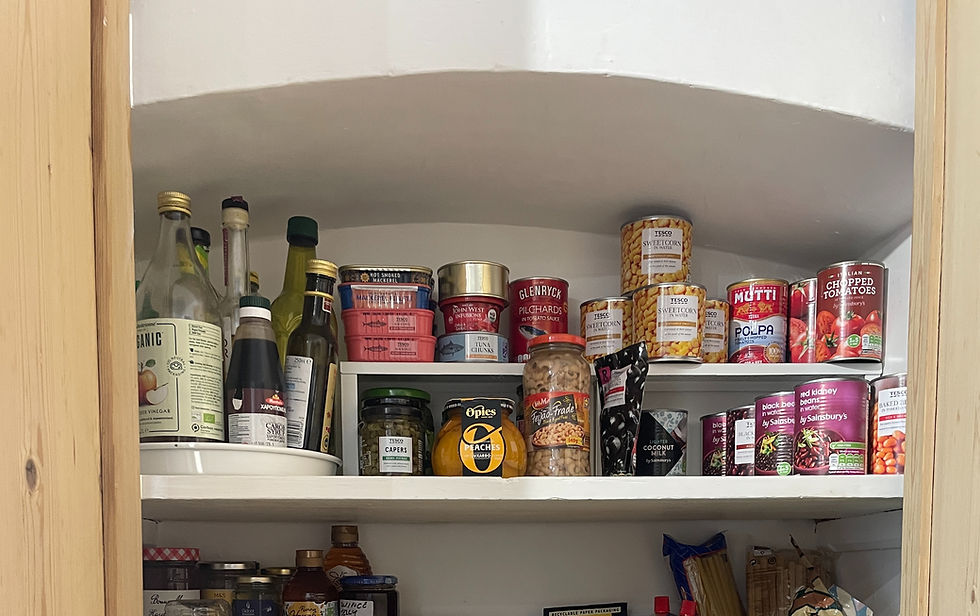 Wooden pantry filled with various jars, canned goods, and condiments on white shelves. Labels include Basmati rice, Hellmann’s, and Mutti.