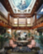 Lobby area of hotel, wooden gallery levels, palm plants, table and chairs