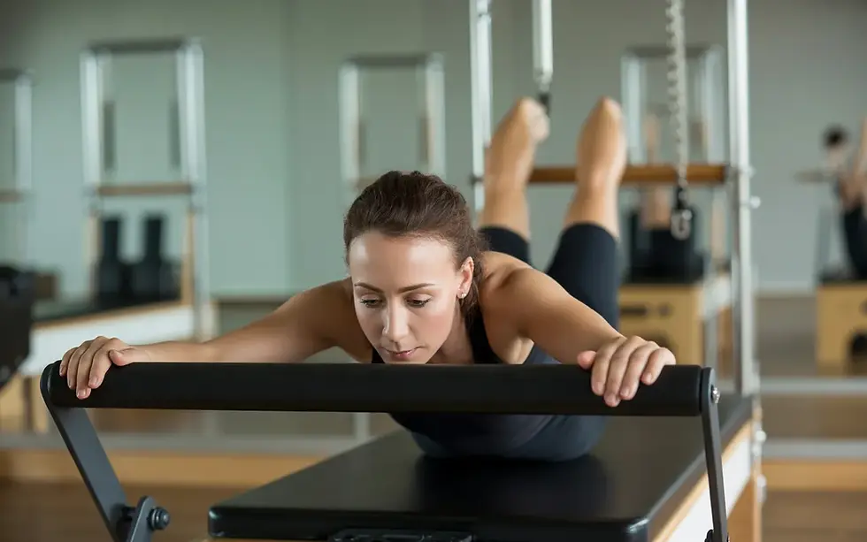 Femme débutante de 30 ans en séance de renforcement musculaire pilates reformer, allongée sur le dos dans un studio lumineux, exécutant un exercice guidé sur machine avec posture correcte.